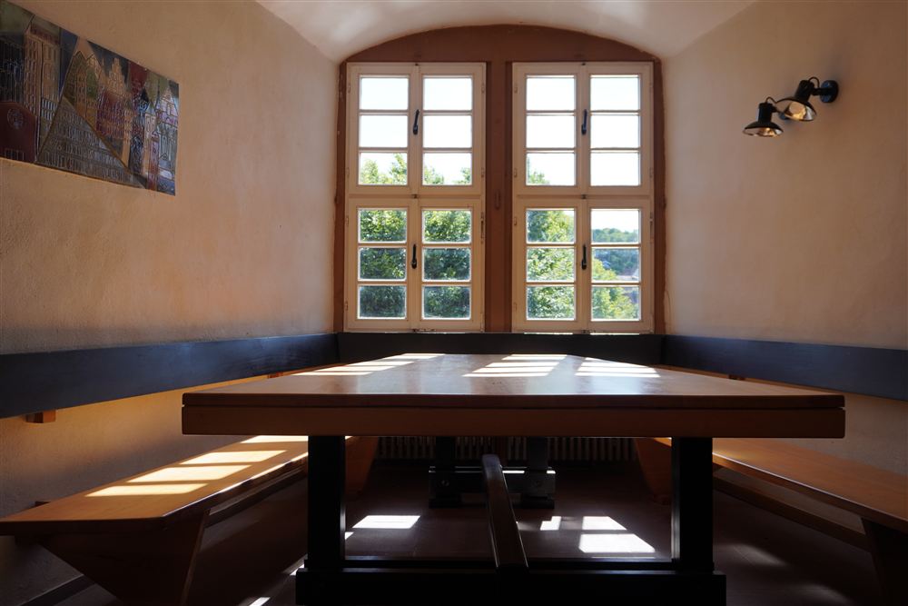 Aufnahme eines Tisches, der vor einem Fenster steht. Das Licht fällt stimmungsvoll ins innere