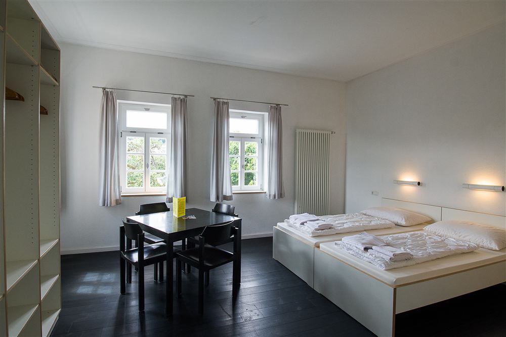 Doppelzimmer mit Doppelbett, Tisch und Stühlen