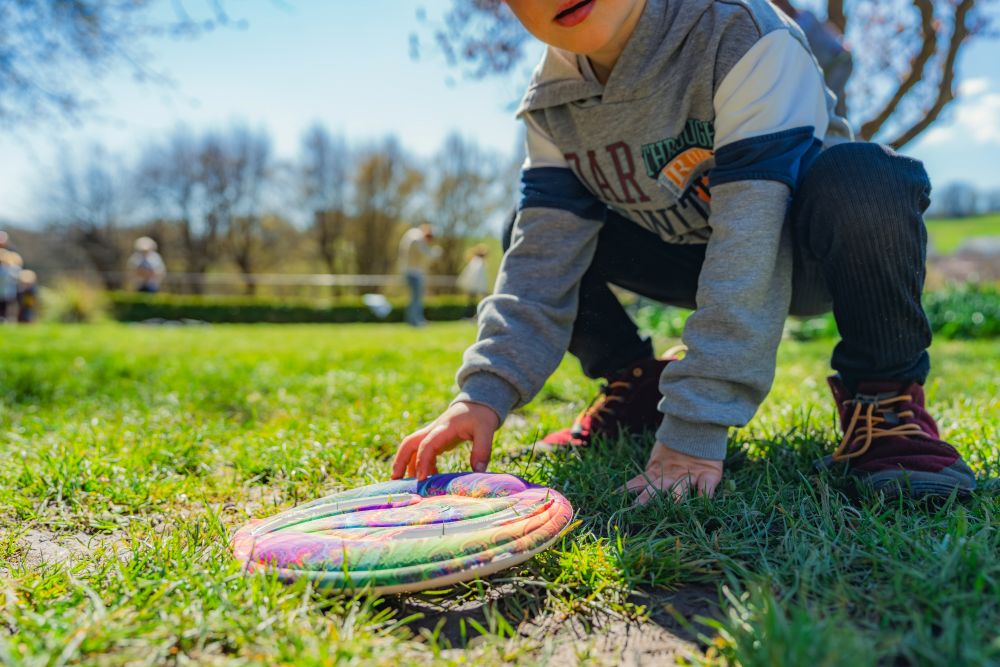 Kind greift nach einer Frisbee-Scheibe