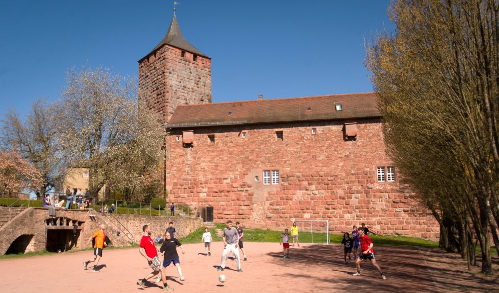 Kinder und Jugendliche spielen auf dem Sportplatz vor der Burg Rothenfels
