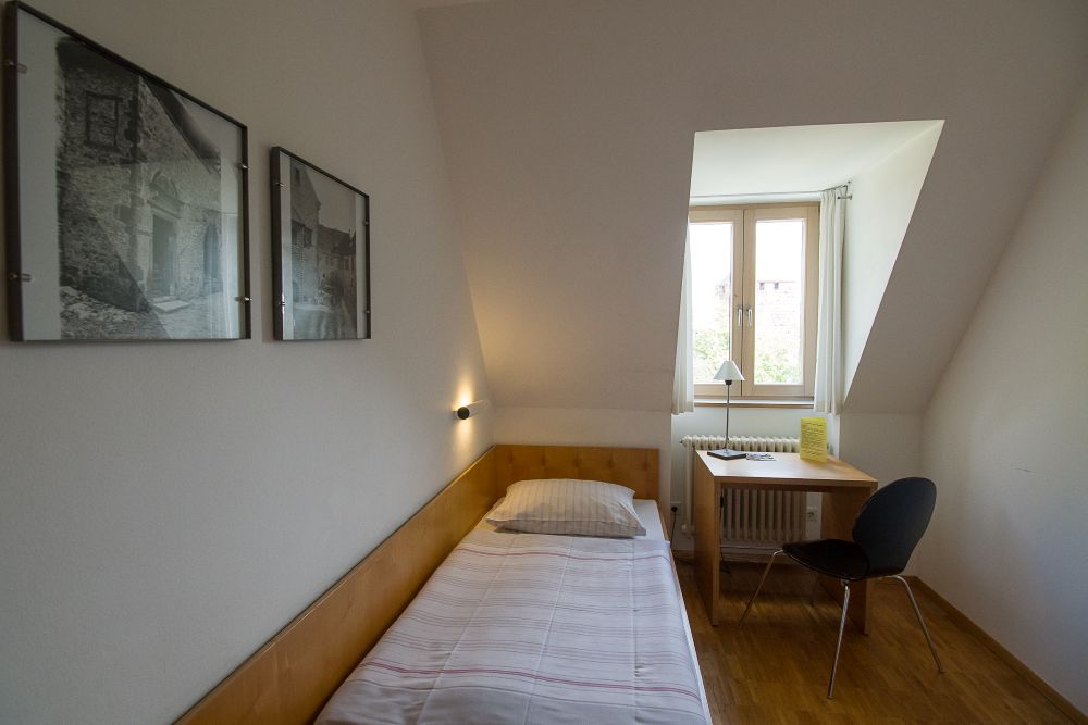 einzelnes Bett mit kleinem Schreibtisch und Stuhl